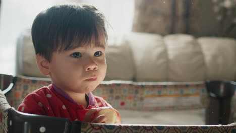 un niño asiático de dos años come una manzana, se para en su cuna