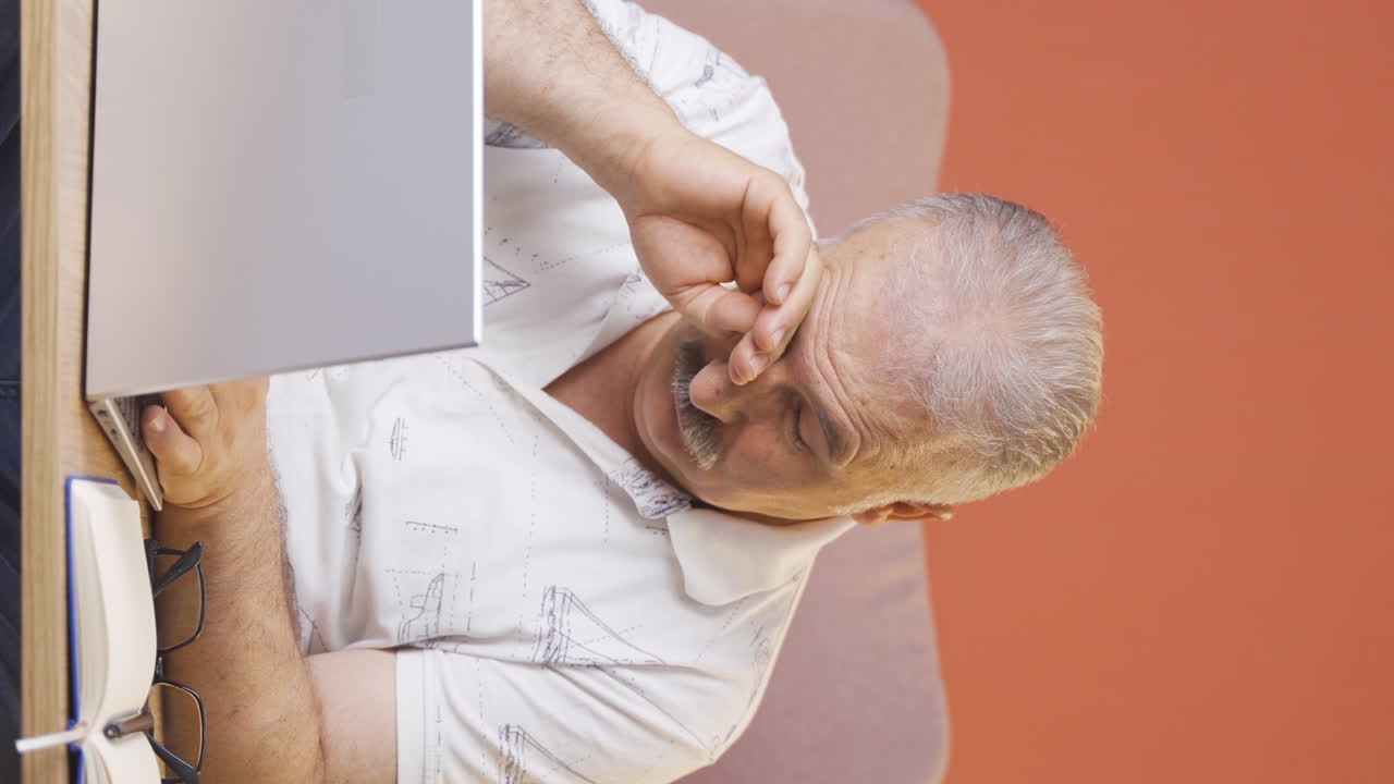 video vertical de un anciano cansado en la computadora portátil.