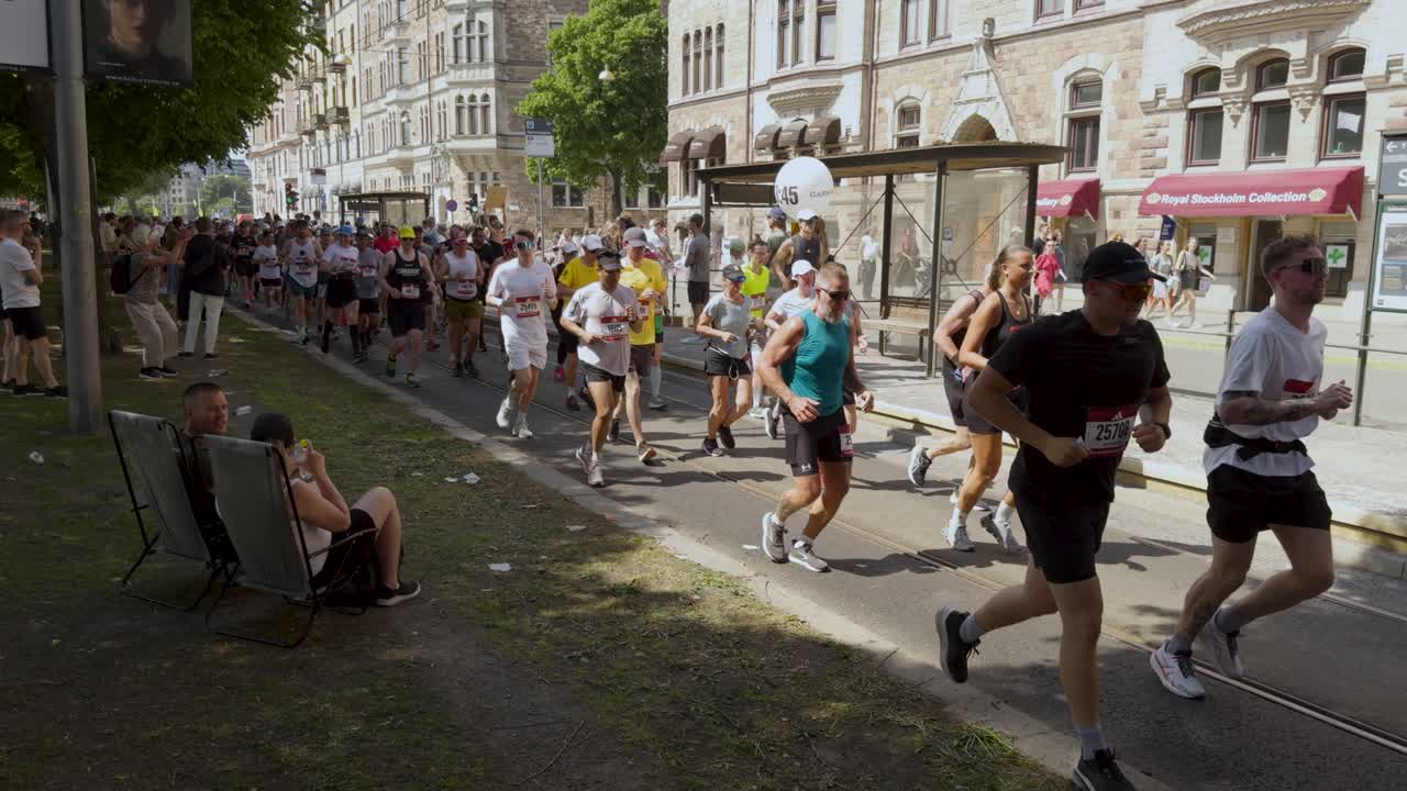 Runners in colorful gear at crowded street marathon on sunny day in Stockholm