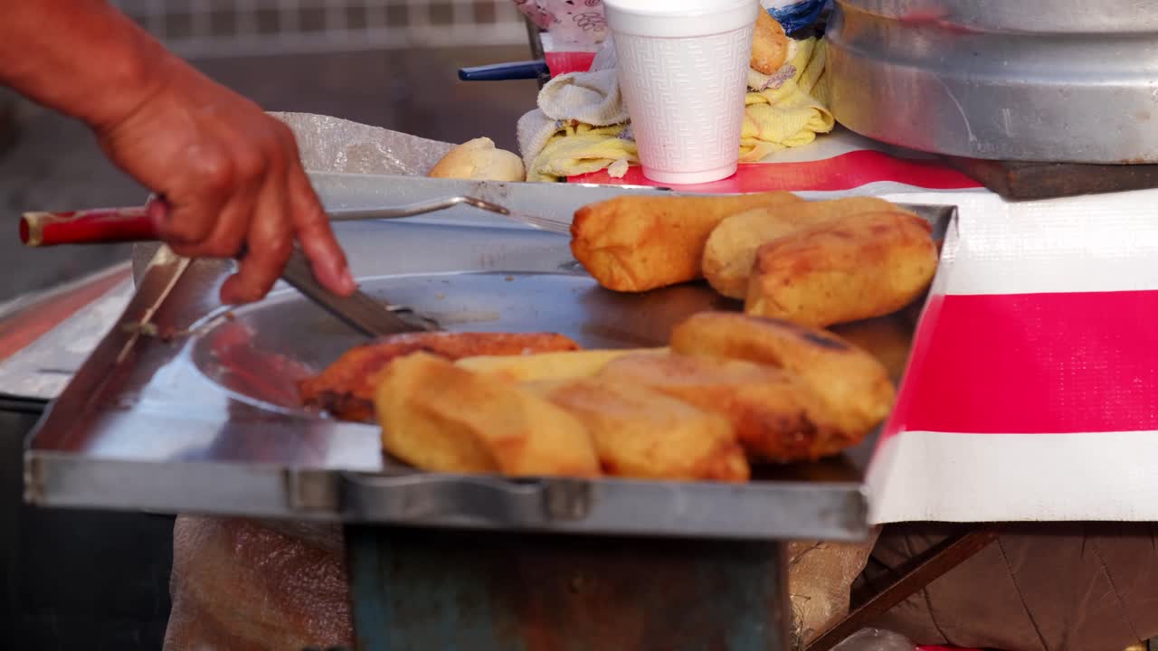 freír tamales vendedor de comida callejera mexicana mano revolviendo buñuelos de maíz en aceite caliente