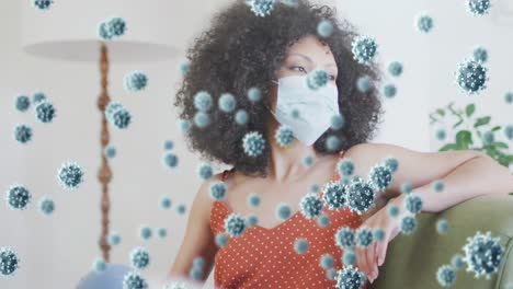 animation of coronavirus cells over african american woman wearing face mask at home