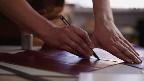 leathersmith cuts material with sharp knife at workplace