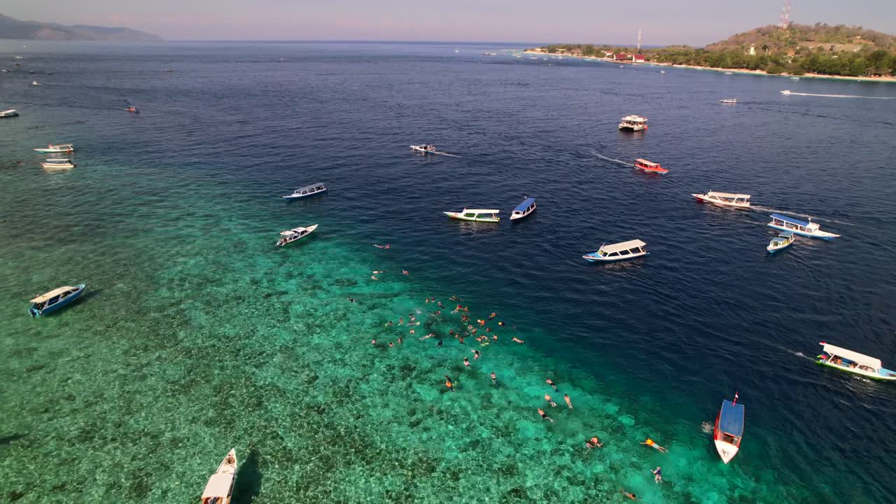 인도네시아 길리 에서 관광객 들 이 스노클링 과 수영 을 하기 위해 투어 여행 보트 들 이 투르코이즈 물 에  ⁇ 매여 있다 - 공중 사진