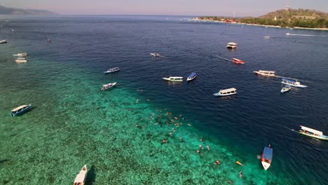 barcos de turismo anclados en aguas turquesas para turistas buceando y nadando en gili, indonesia - vista aérea