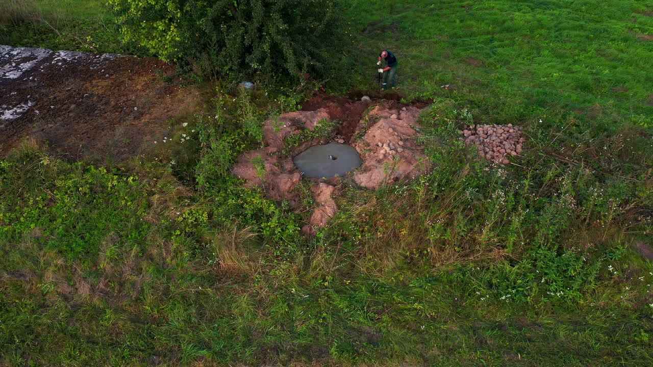 Man digging ground with shovel in rural area, aerial view