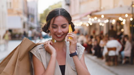 woman shopaholic consumer after shopping sale with full bags with gifts outdoors, talking on phone