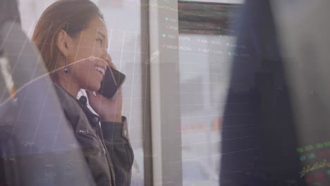 animation of trading board, smiling biracial woman talking on cellphone while travelling in bus