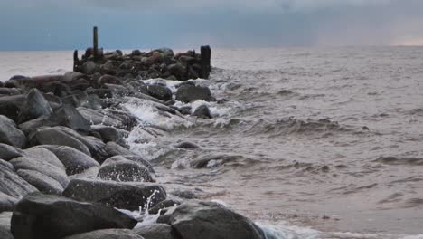 the sea wave washes away the old abandoned stone pier