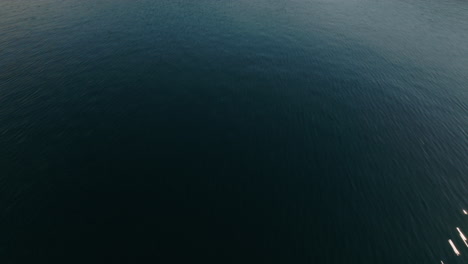 fast paced aerial over lake tilting up to reveal mountains with reflection