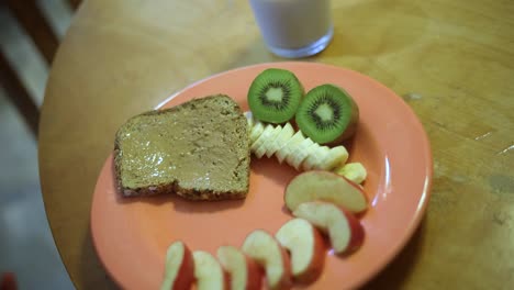 Zeitlupenaufnahme-Von-Jemandem,-Der-Einen-Teller-Voller-Frühstücksspeisen-Auf-Einen-Holztisch-Stellt