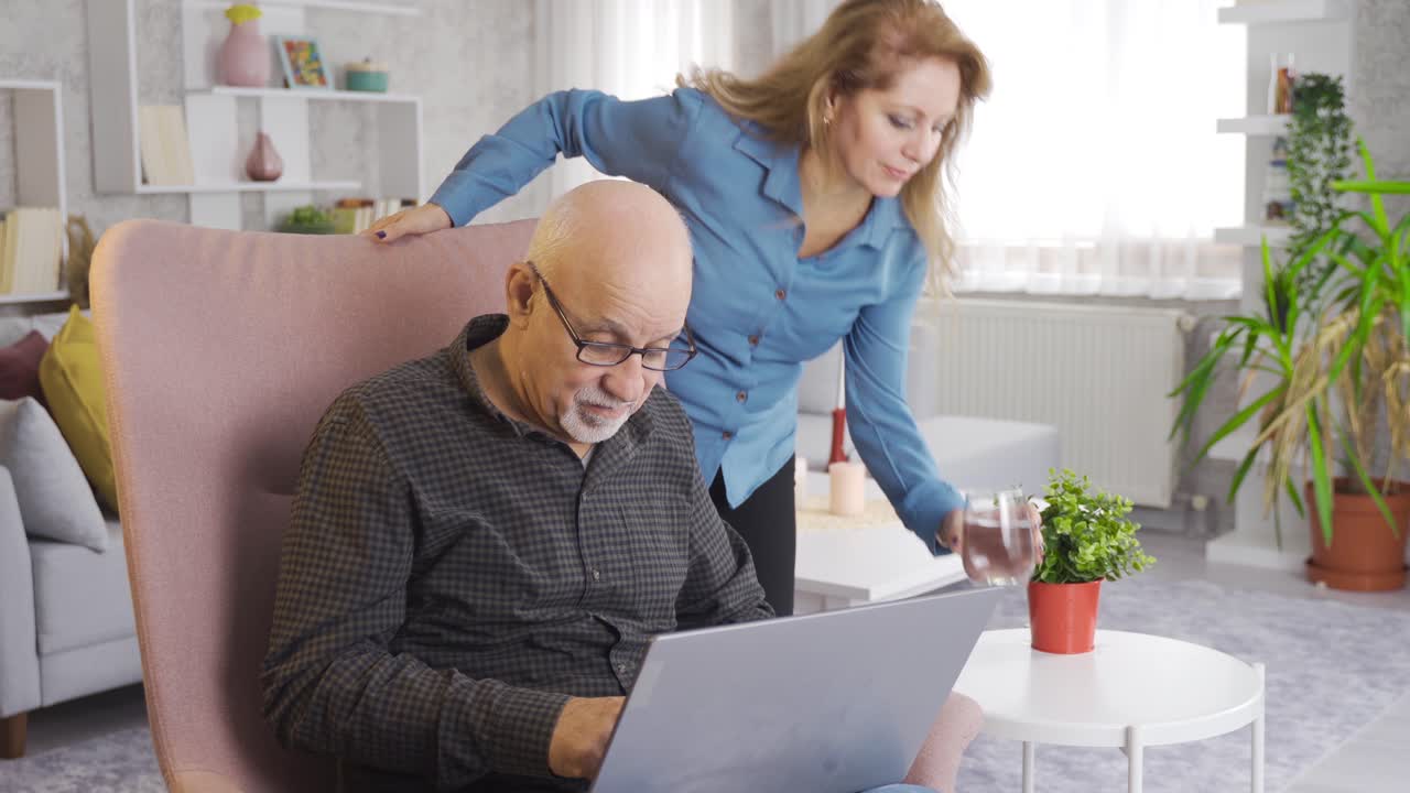 Mature couple on sofa at home using computer, daily life.
