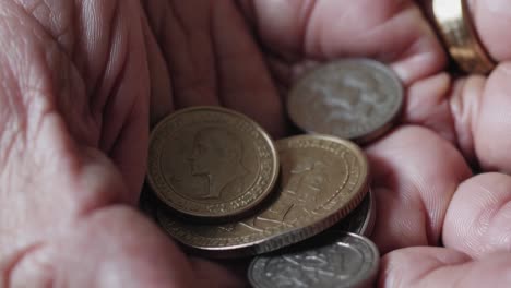 close up of wrinkled hands holding few coins, symbolizing financial struggles, economic hardship, and the impact of inflation on vulnerable populations
