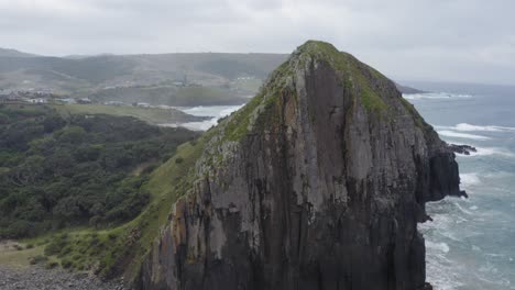 Drone-circle-around-rocky-cliff-with-green-grass-and-rolling-hills-in-Transkei,-South-Africa