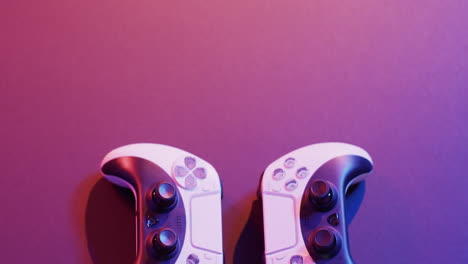 video of close up of video game pad controllers with copy space on neon background
