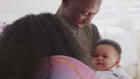 father and daughter dressed as fairy sitting in bedroom playing peekaboo with baby brother