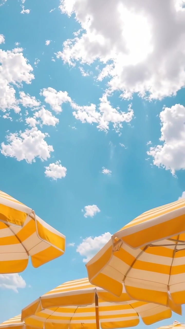 Sombrillas de Playa a Rayas Amarillas Bajo Cielo Azul con Nubes en Movimiento