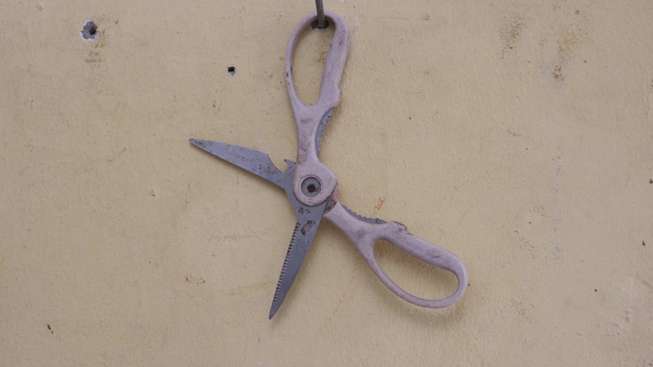 Rosa Schere hängt an der Wand.