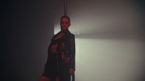 woman pole dancing in a dark studio