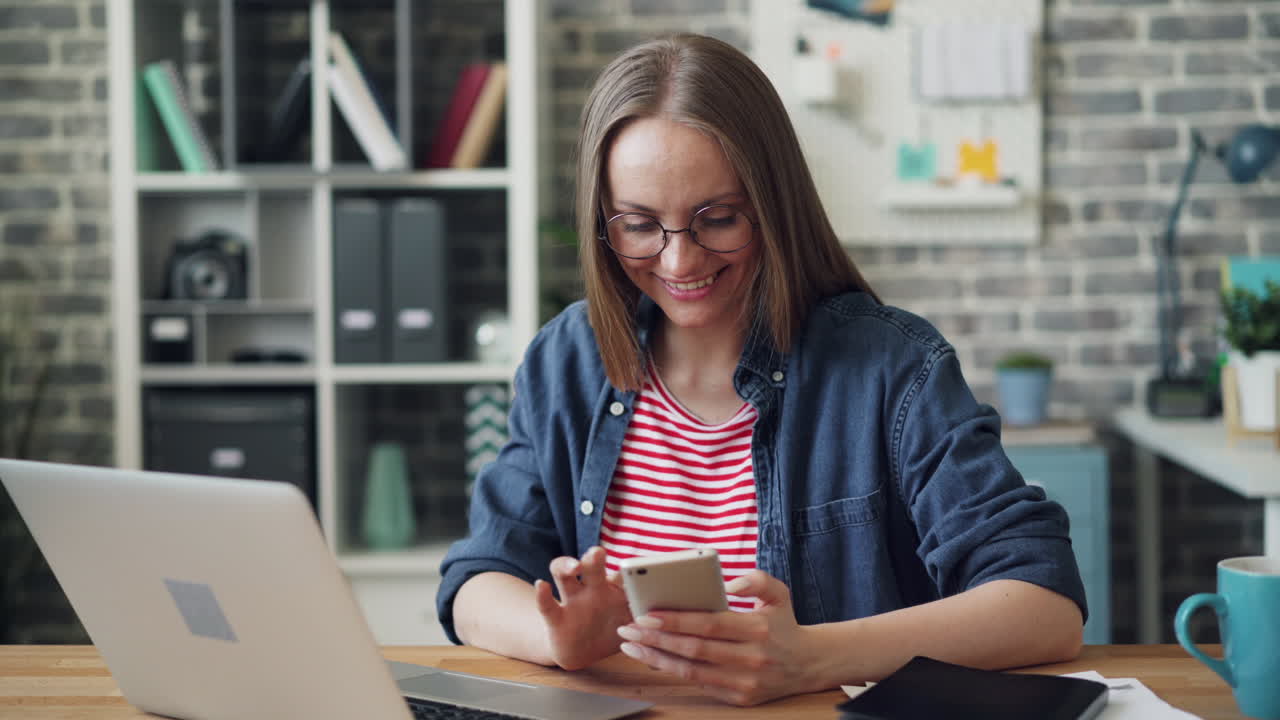 Woman Working on Laptop and Phone in Home Office