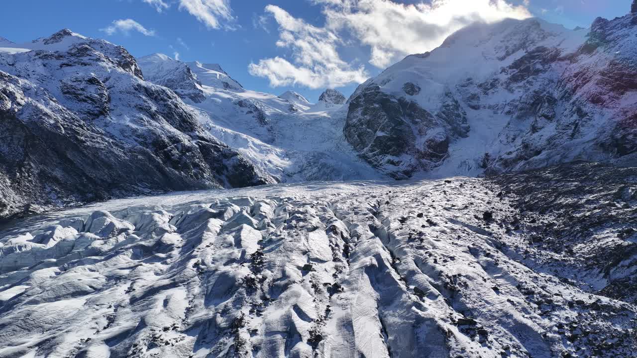 A glacier winds through rugged snow-covered peaks under a clear sky. Morteratsch Glacier