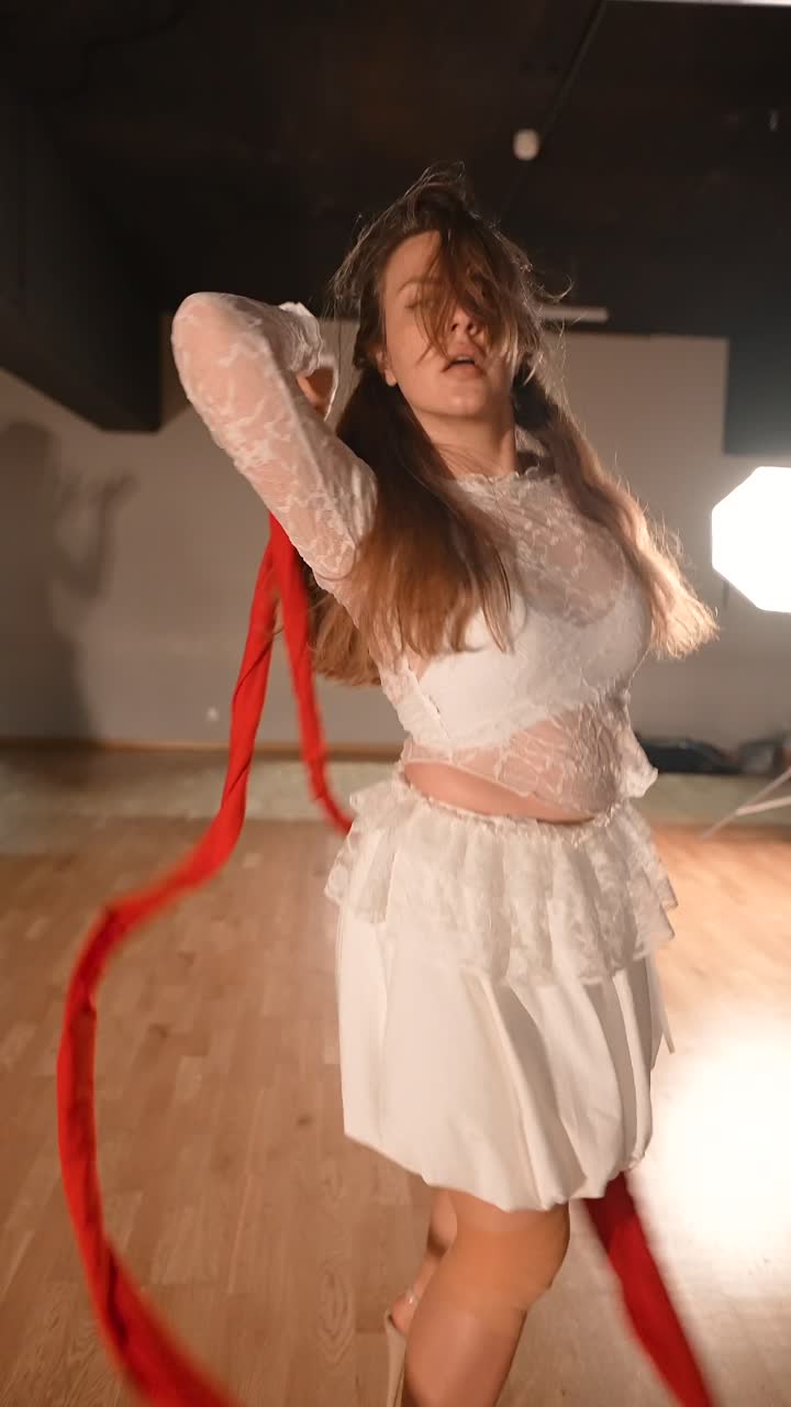 Woman dancing with red ribbon in a studio setting