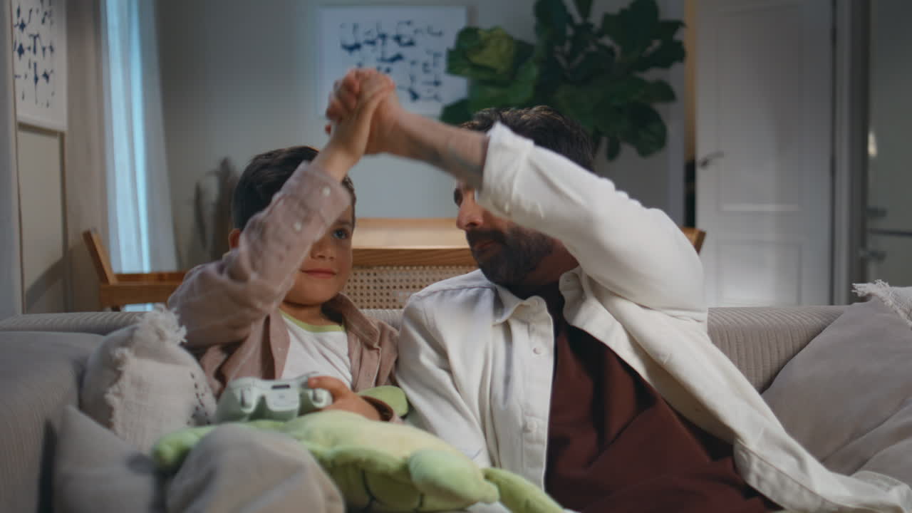 Excited family video gaming having fun at evening. Emotional father trying win