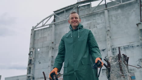 happy ecologist in abandoned place. man survivor holding gas mask in hands and smiles breathing fresh air on the background of destroyed building.