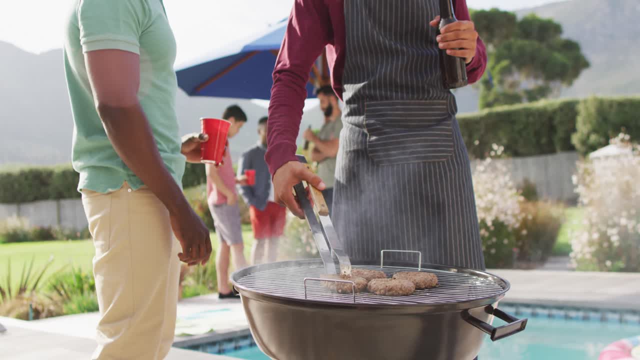 Happy diverse male friends talking and drinking beer in garden on sunny day