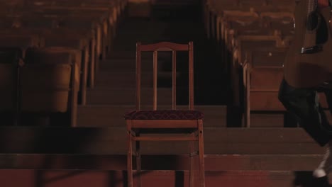 a handsome guy plays an acoustic guitar in an abandoned cinema. the musician sings a song and accompanies on the guitar