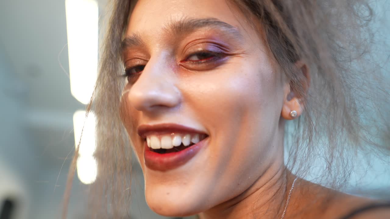 Närbild på ung kvinna med uttrycksfull makeup och rufsigt hår