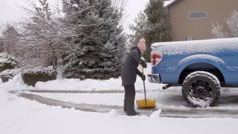 senior, mujer madura paleando nieve después de una tormenta