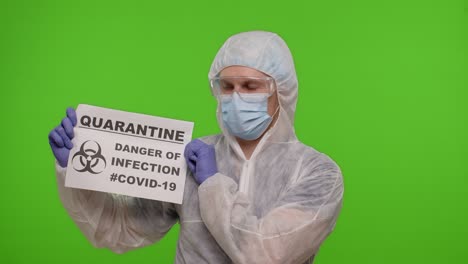 doctor in ppe suit showing warning text slogan on paper - quarantine danger of infection covid-19