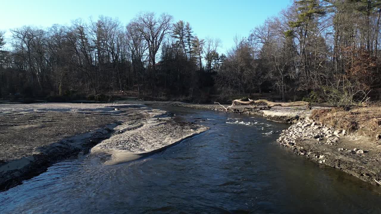 Backward shot of a river flow that is badly eroded with a dry trees