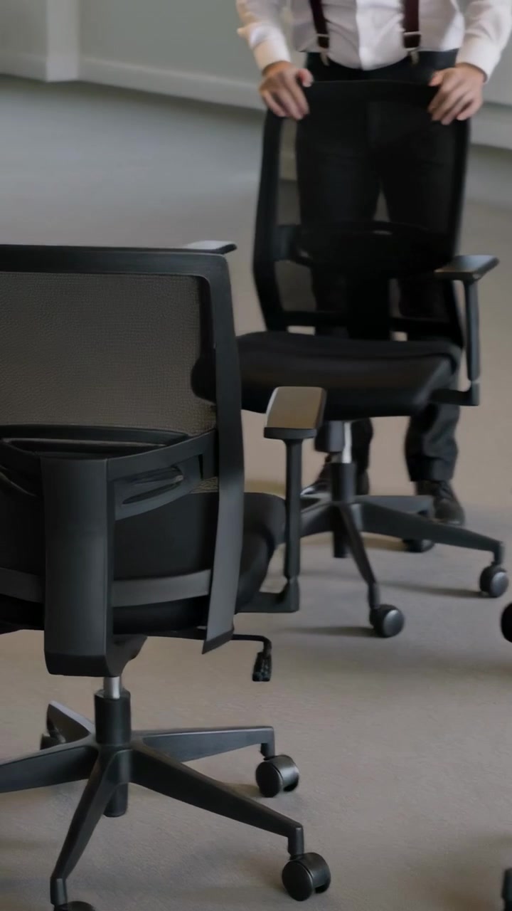 Video verticale: Entrano da sinistra due uomini che sistemano sedie in un ufficio vicino alle finestre, uno con le bretelle.