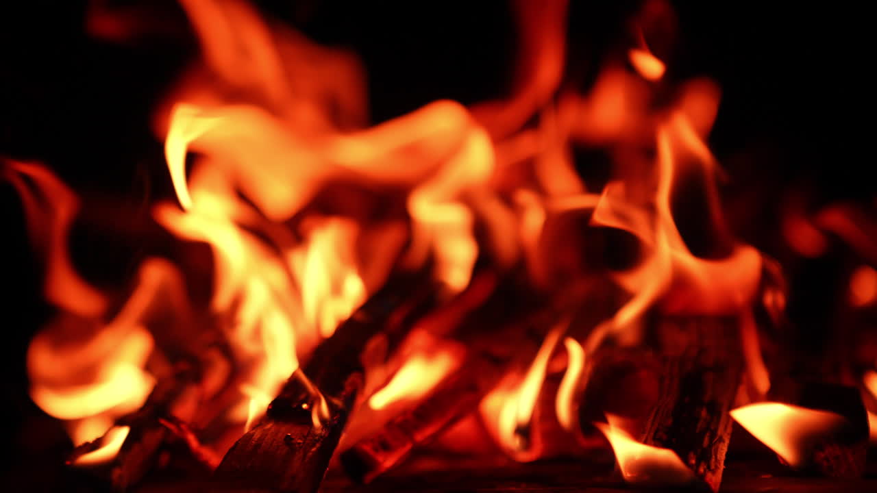 Il legno si consuma nel falò. Immagine sfocata del falò nell'oscurità. Primo piano.