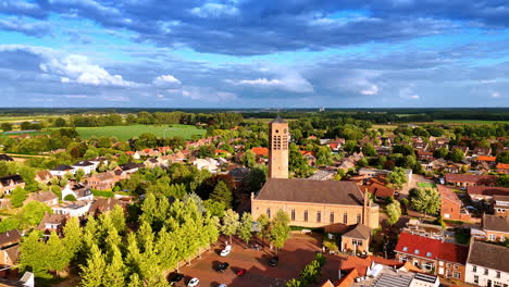 sunny scenery of vierlingsbeek, netherlands from drone. approaching the gothic building of saint lawrence church with a clock tower