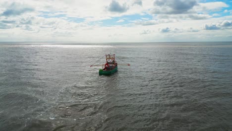 barco de pesca, arrastrero frente a la costa este del reino unido, navegando hacia el sol en un mar agitado
