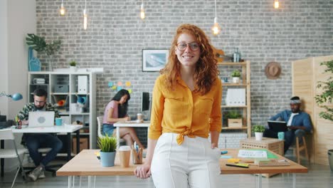 slow motion of pretty smiling girl standing in office looking at camera