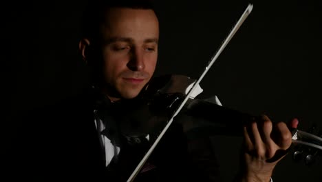 violinist man playing the violin on a black background. close up