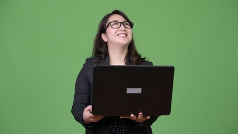 una hermosa mujer de negocios asiática madura usando una computadora portátil contra un fondo verde
