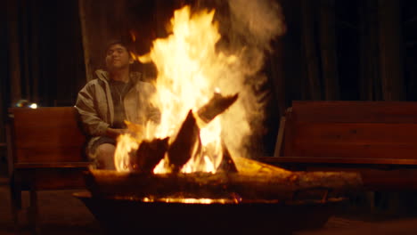 man relaxing by a campfire at night