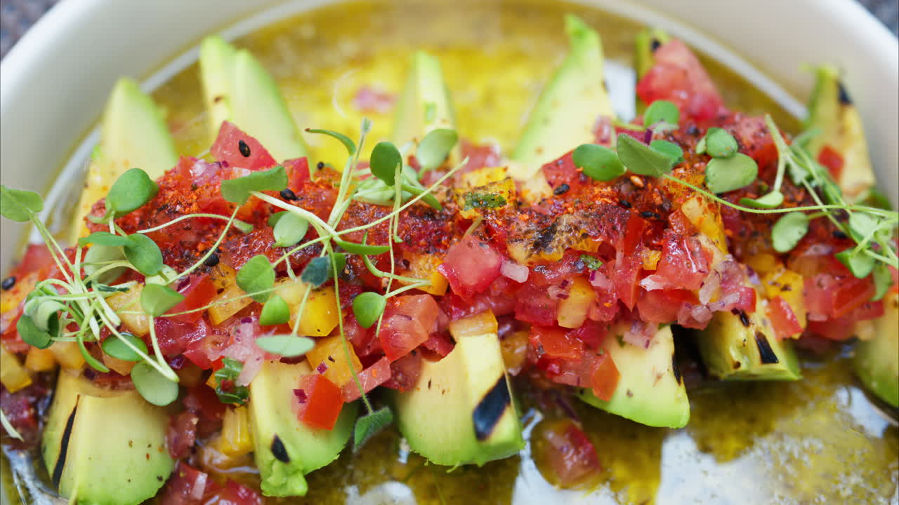 Close up of a woman eating avocado with cut up tomatoes