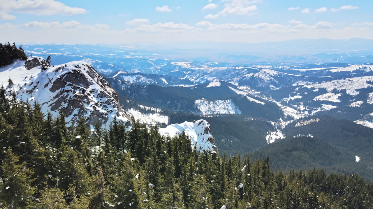 Vista aerea dei Carpazi in primavera, Romania, ripresa da un drone. Cime rocciose e valli parzialmente coperte da foreste innevate