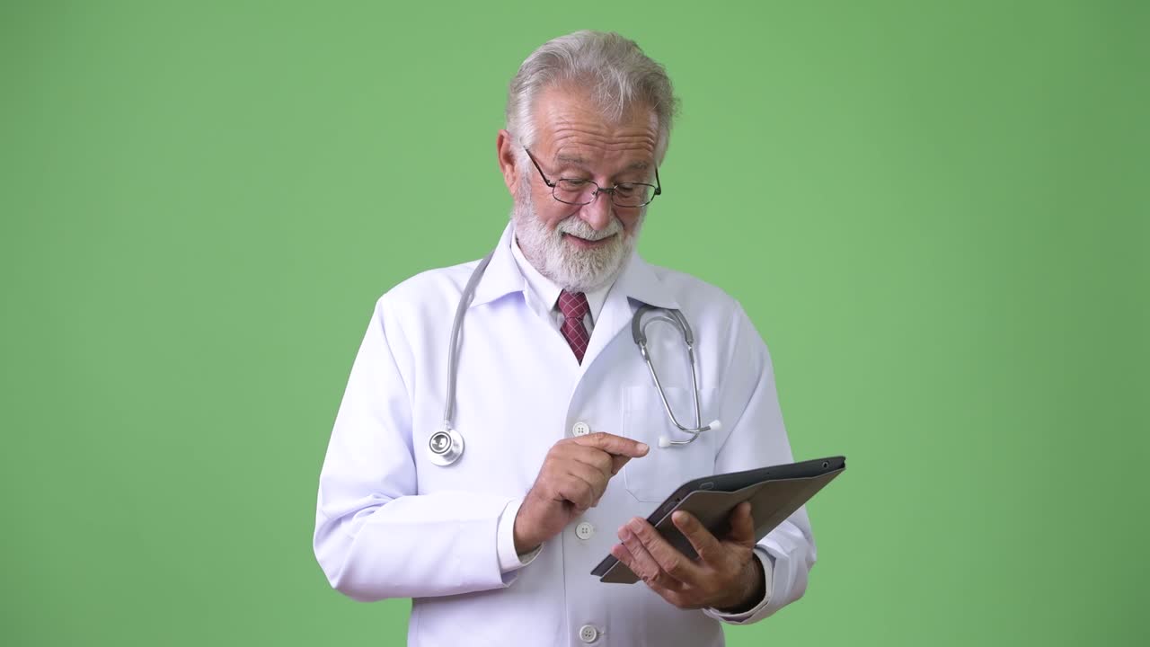 Medico anziano affascinante con la barba su sfondo verde.