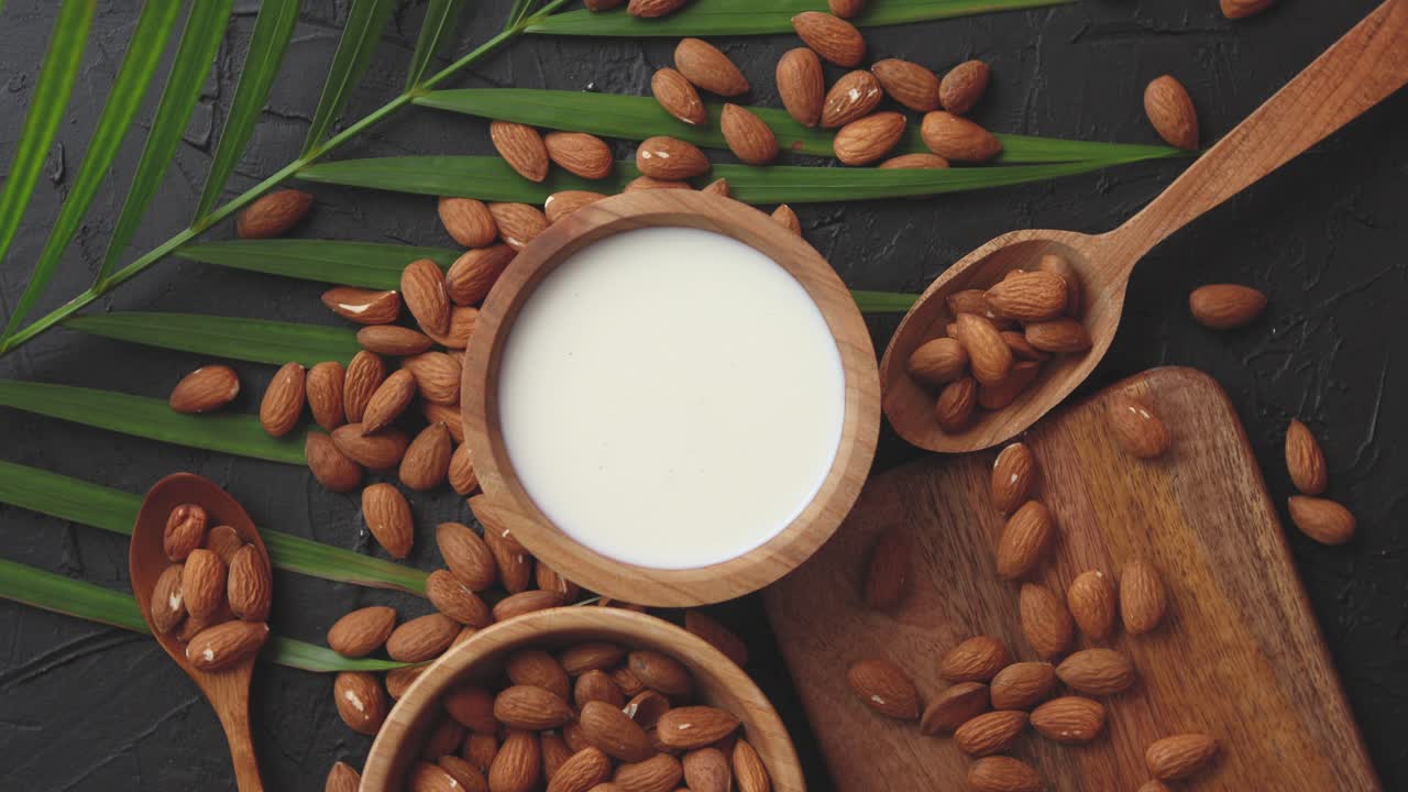 primer plano de almendras en tazón de madera y leche de almendras