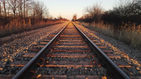 endless steel railway tracks with sunset glow, dolly forward fast view