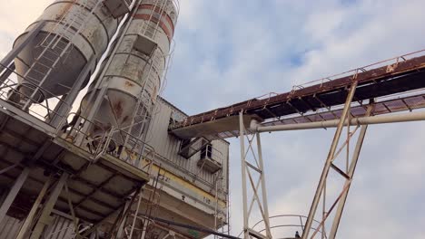 Birds-soaring-above-vintage-industrial-silos,-decorated-with-metal-ladders,-capturing-the-spirit-of-industrial-heritage-and-urban-exploration