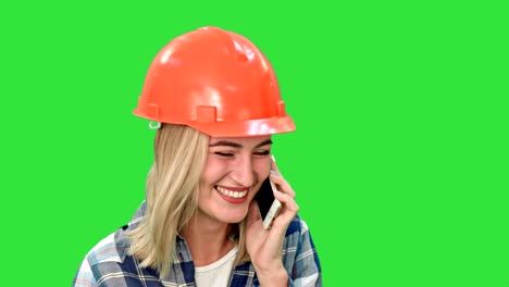 hermosa ingeniera de sombrero duro llamando a través de un teléfono celular en una pantalla verde, llave de croma