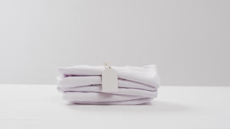 Video-of-stack-of-folded-white-t-shirts-with-copy-space-on-white-background