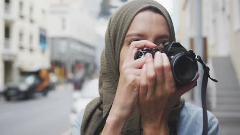 woman wearing hijab taking photo in the street